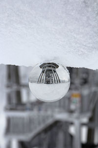 Close-up of crystal ball hanging on glass against sky