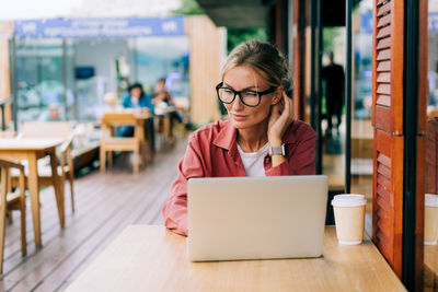 Young attractive caucasian business woman sitting in a cafe working on a laptop.