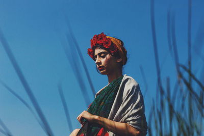 Low angle view of woman standing against clear blue sky