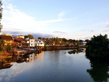 Buildings by river against sky in city