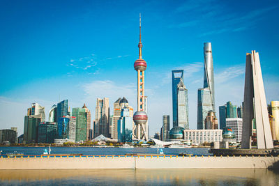 Communications tower in city against sky