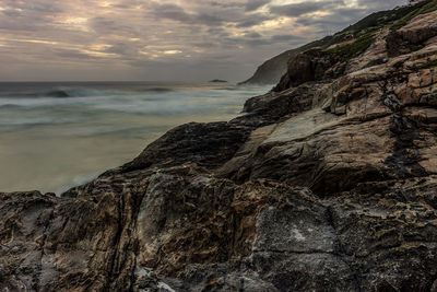 Rock formation on beach against sky during sunset