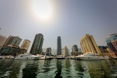 Modern buildings by river against sky in city