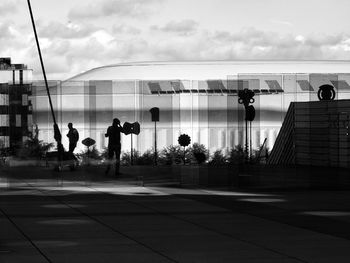 Silhouette people walking in city against sky