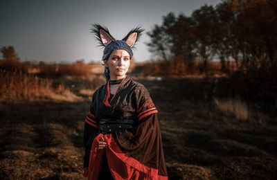 Portrait of young woman wearing costume standing on field