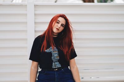 Portrait of beautiful young woman standing against wall