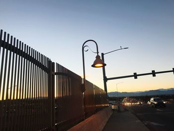 Illuminated street lights against sky at sunset