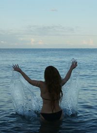 Rear view of woman standing in sea