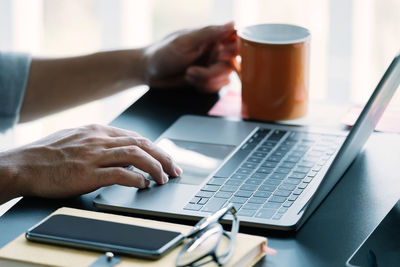 Cropped hands of businessman using laptop on table