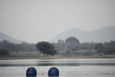 Plastic containers floating in lake against sky