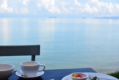 Coffee cup on table against sea