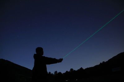 Man pointing night sky with laser
