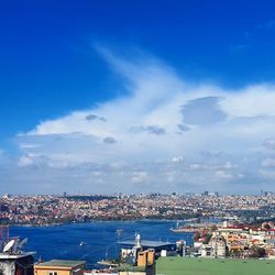 Cityscape in front of sea against blue sky