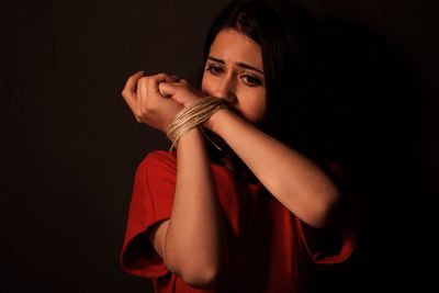 Woman hands tied with string against black background