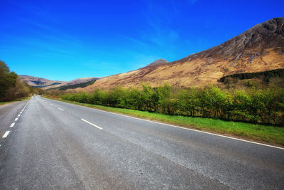 Road by mountain against blue sky