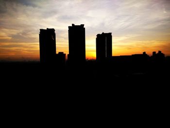 Silhouette buildings against sky at sunset