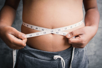 Midsection of woman measuring stomach