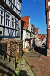 Footpath amidst buildings against blue sky