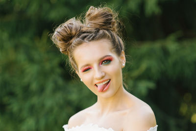 A cheerful funny young woman or girl with bright makeup and a funny hairstyle squinted one eye