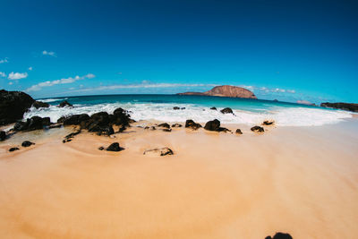 Scenic view of beach against blue sky