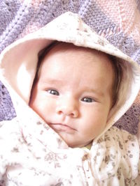 Portrait of cute baby girl lying on bed