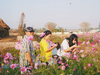 Family standing at cosmos field against sky