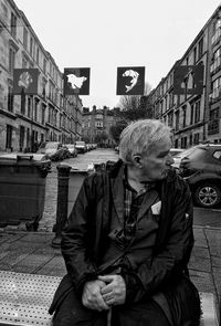 Midsection of man holding umbrella in city against sky