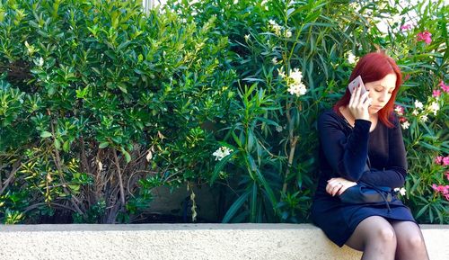 Young woman using mobile phone while sitting in park