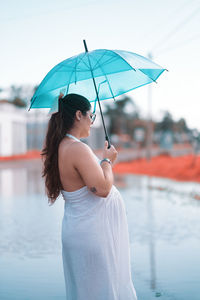 Young woman with umbrella standing at beach
