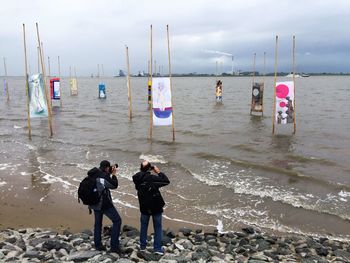 People at beach against sky