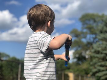 Rear view of boy standing against sky