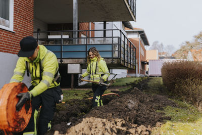 Male and female workers laying cables in trench