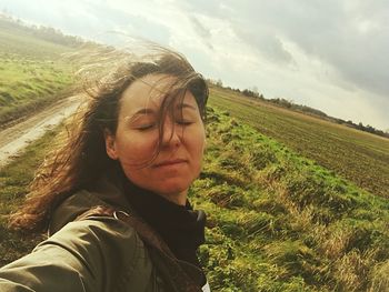 Woman with closed eyes on landscape against sky