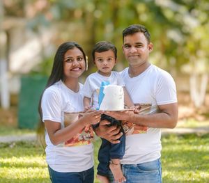 Portrait of smiling young woman using mobile phone while standing outdoors