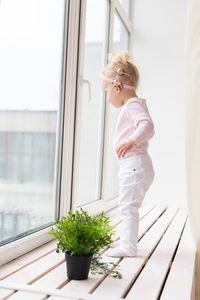 Side view of woman standing by window