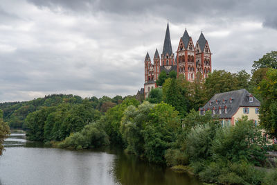 Panoramic view of river amidst buildings and trees against sky