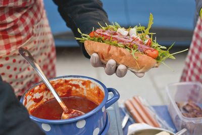 Midsection of vendor holding hot dog at market stall