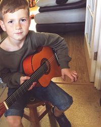 Portrait of boy playing guitar at home