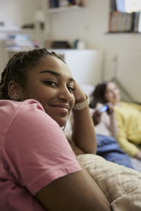 Smiling female teenager with friends in background at home