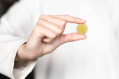 Close-up of a woman holding a pill, a herbal capsule in her hand against the background of a white