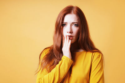 Portrait of young woman against yellow background