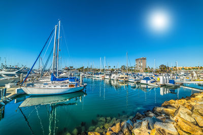 Sailboats moored at harbor against clear blue sky