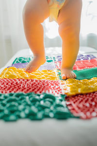 The kid walks barefoot on multi-colored massage rugs.