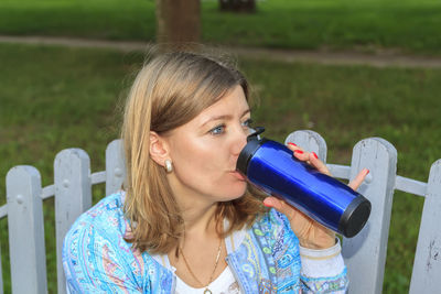 Close-up of woman drinking water sitting outdoors