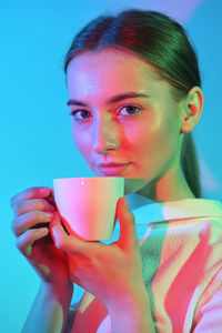 Close-up portrait of young woman drinking coffee at home