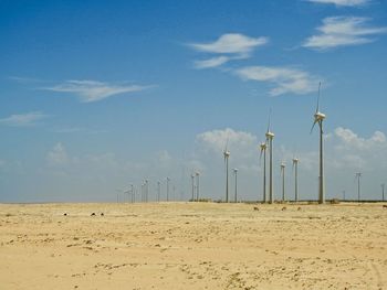 Scenic view of beach against sky with eolic turbines 