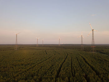 Wind turbines on field against sky