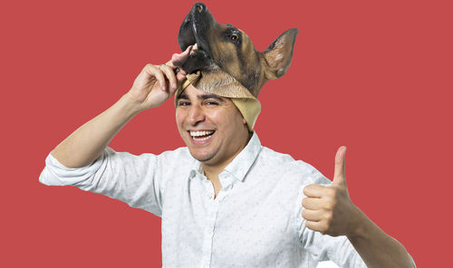 Portrait of smiling young man against red background