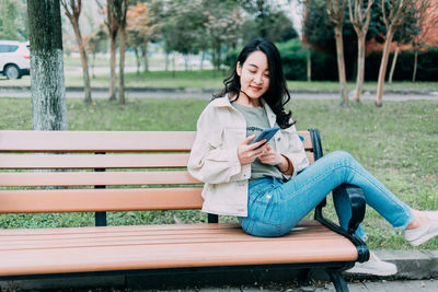 Young woman sitting on bench in park