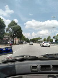 Cars on road against sky seen through car windshield